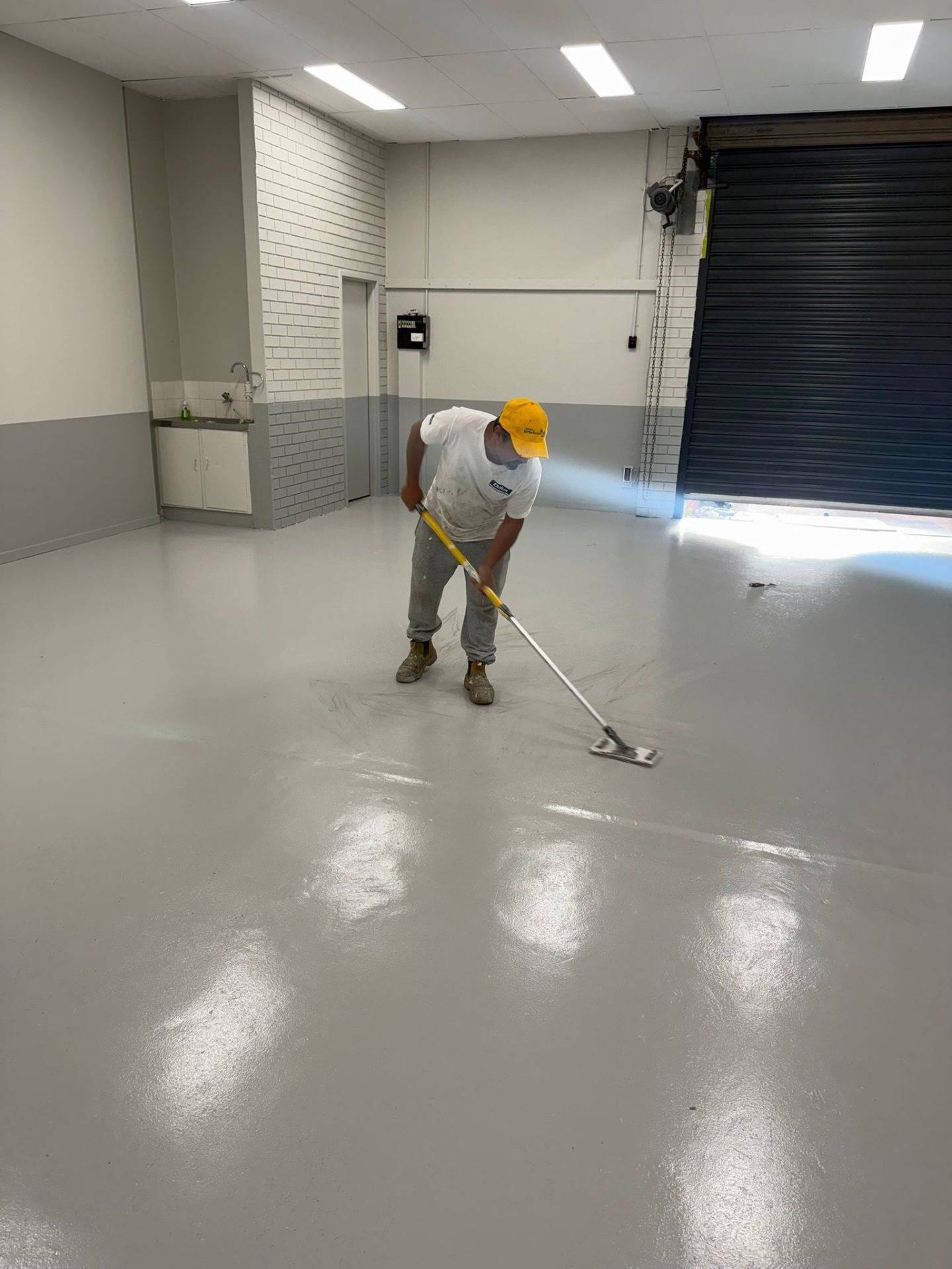 Painter applying an epoxy floor coating in a commercial unit