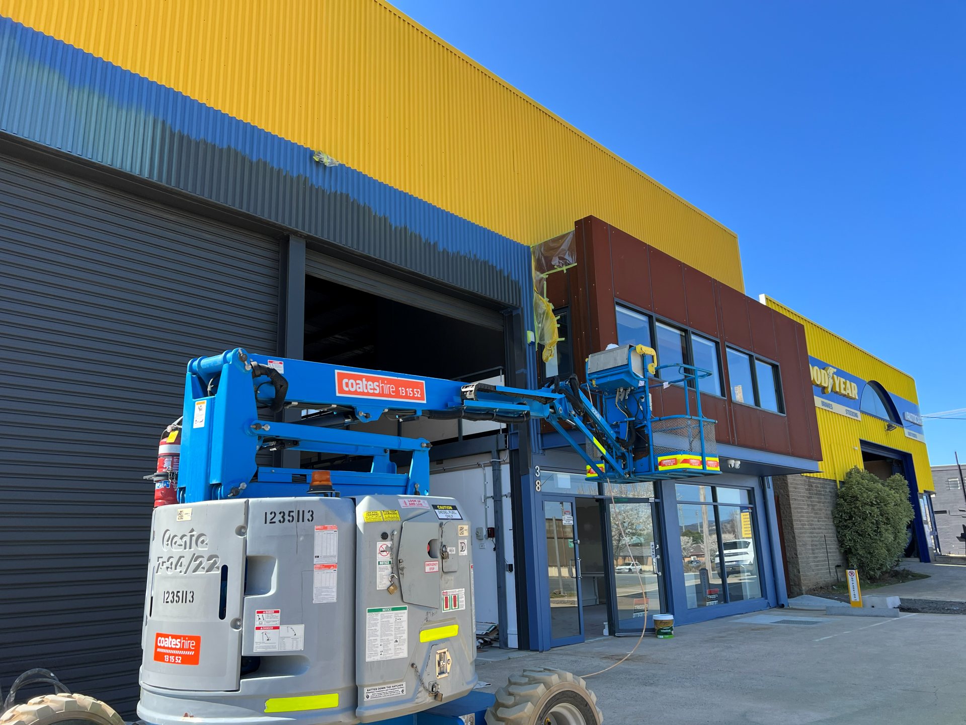 Boom lift painting a large commercial warehouse facade