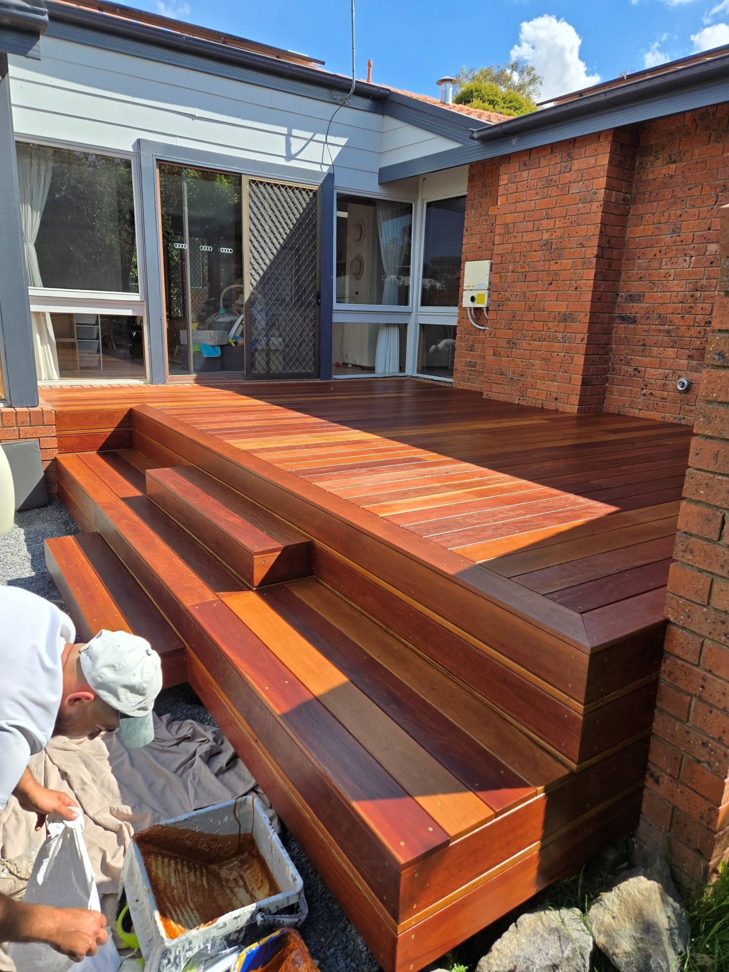 Recently stained timber deck against a red brick home