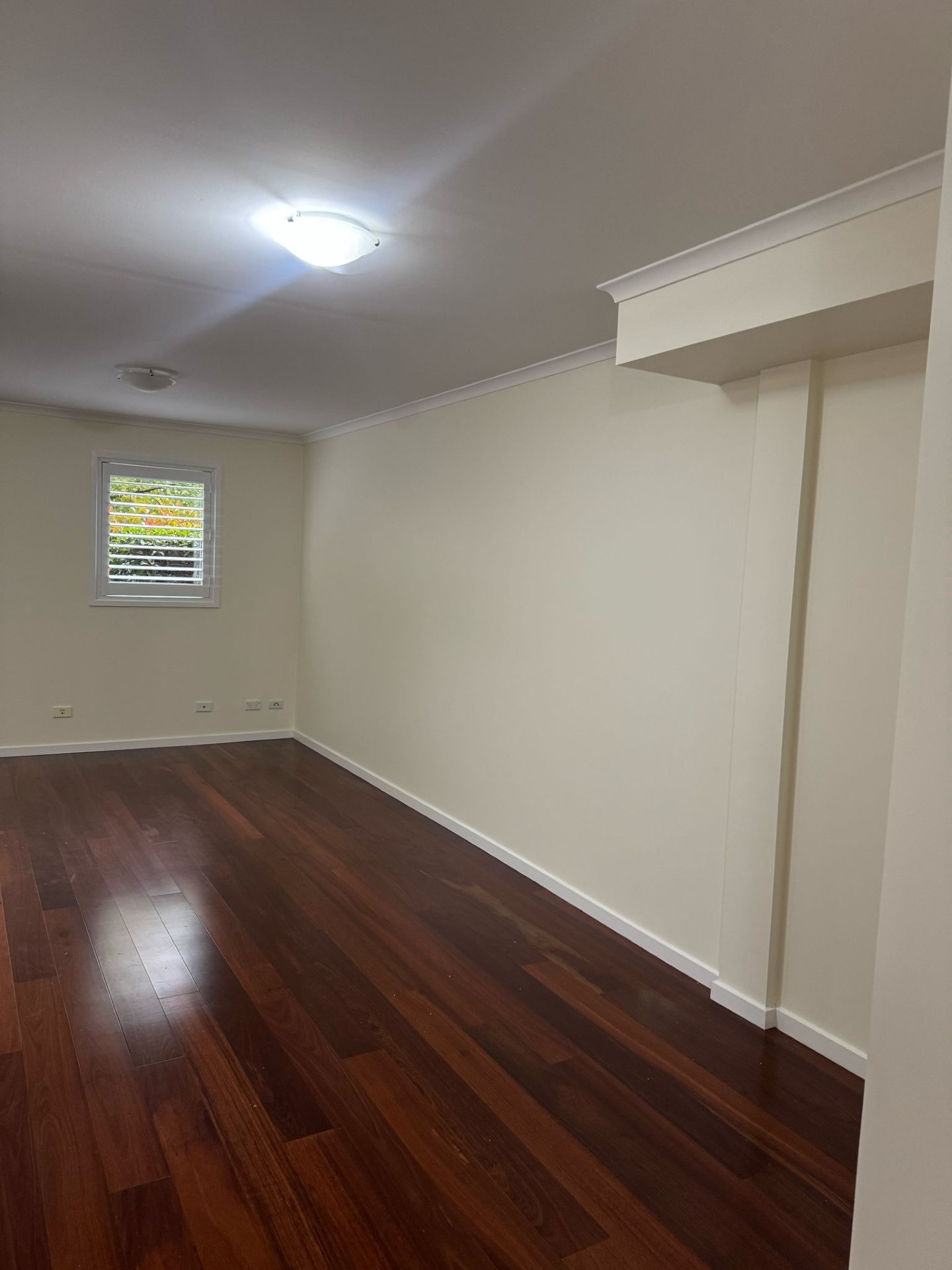 Freshly painted empty room with timber flooring and plantation shutters